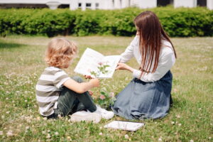 Tutor reading with a student outdoors during a summer tutoring session in Greenwich, CT to prevent summer learning loss