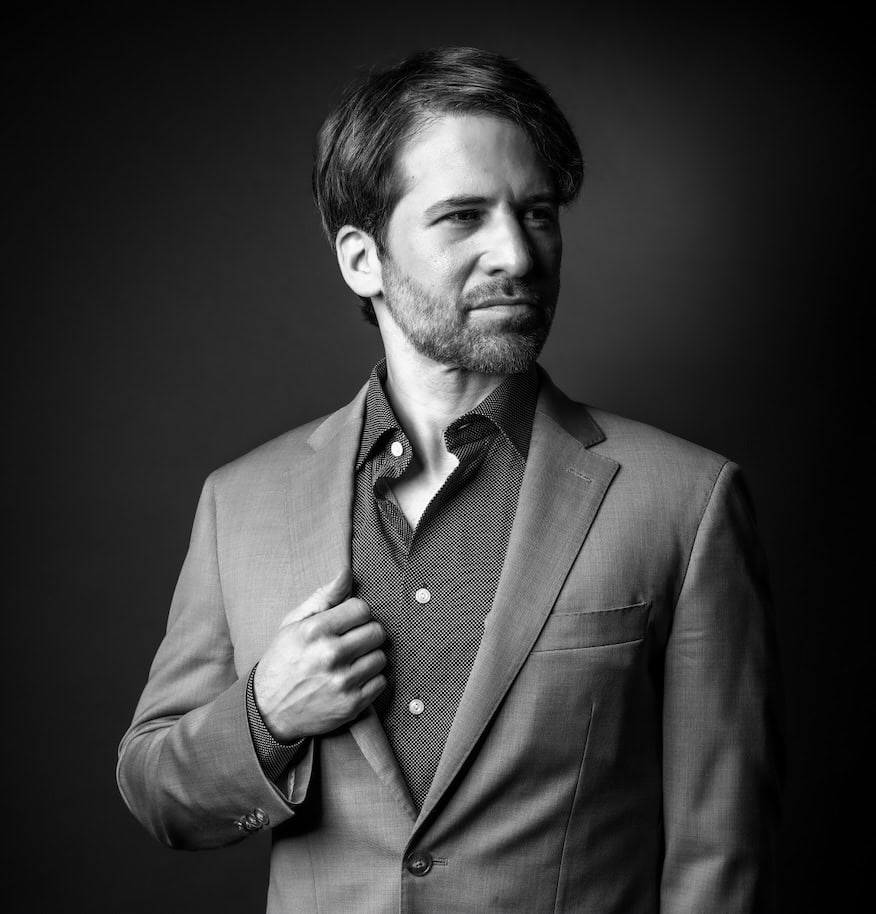 Aron Boxer, M.Ed., S.P.E., Founder and CEO of Diversified Education Services, in a professional suit, demonstrating a confident demeanor against a dark background.