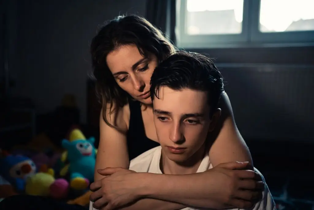 Mother supporting teenage son with severe autism and visible skin-picking scars, illustrating the reality of autism parenting and daily caregiving challenges