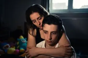 Mother supporting teenage son with severe autism and visible skin-picking scars, illustrating the reality of autism parenting and daily caregiving challenges