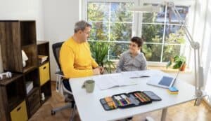 Male executive function coach working one-on-one with a teenage student during an academic planning session.